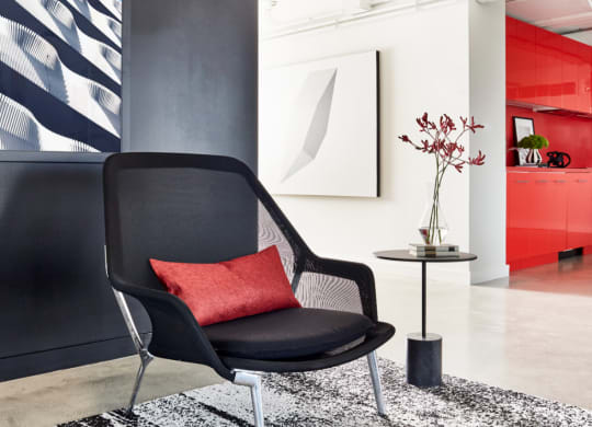 a black chair with a red pillow in a living room