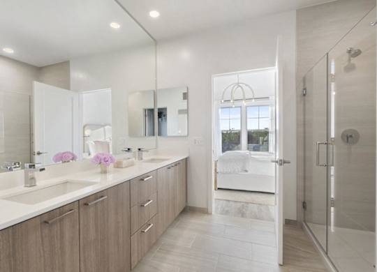A bathroom with a white counter top and a walk in shower.