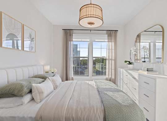 A bedroom with a large bed, a dresser, and a mirror.