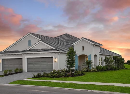 A white house with a grassy lawn and pink sky. at Marisol, Bradenton, FL, 34211