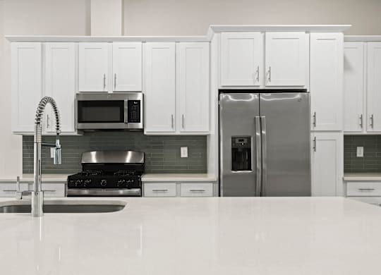 A kitchen with white cabinets and a stainless steel refrigerator.