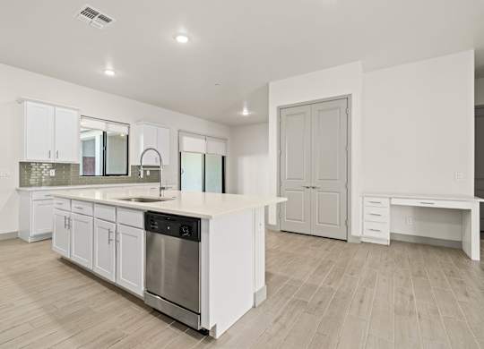 A modern kitchen with white cabinets and a wooden floor.