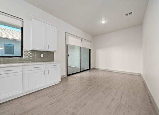 A kitchen with white cabinets and a wooden floor.