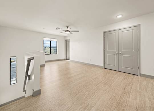 A room with a ceiling fan and a large door.