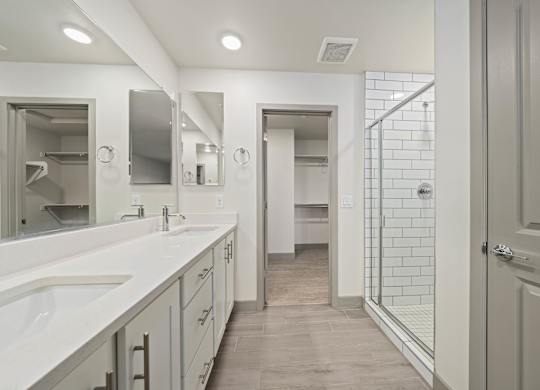 A bathroom with a walk-in shower and double sinks.