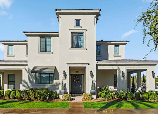 A large, two-story house with a front yard and a driveway.