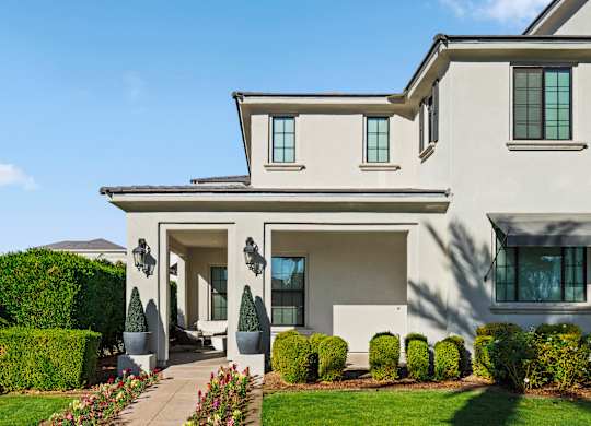 A modern house with a white exterior and a large front yard.