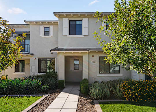 A modern house with a grey front door and a small garden in front.