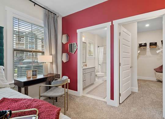 A bedroom with a red accent wall and a white door leading to a bathroom.at 198 Milltown Apartments, Burlington, NC  