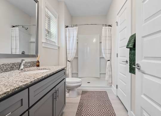 A bathroom with a toilet, sink, and shower.at 198 Milltown Apartments, Burlington  