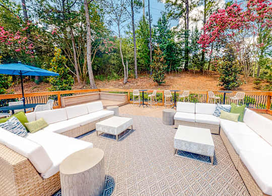 a patio with couches and tables and a deck with trees at Inverness Cliffs, Birmingham, AL, 35242