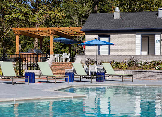 a swimming pool with chairs and umbrellas next to a house at Inverness Cliffs, Alabama