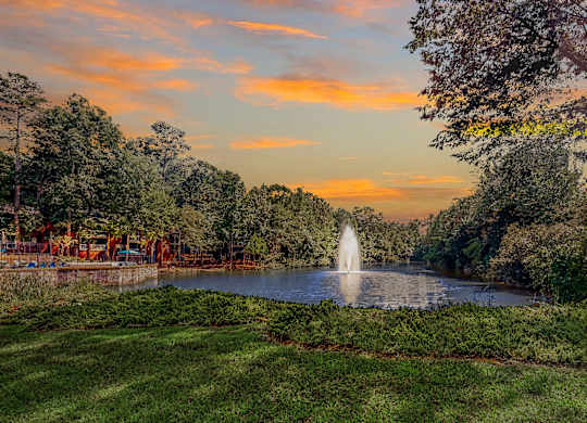a fountain in the middle of a pond at sunset at Inverness Cliffs, Birmingham, Alabama