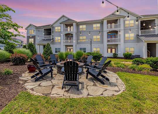 A large building with a patio and chairs around a fire pit. at Concord Ridge Apartments, Concord, NC