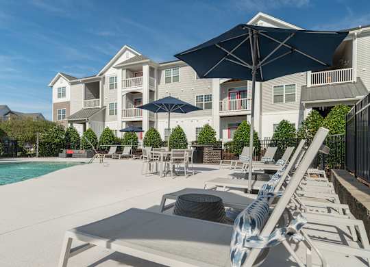 A sunny day at the pool with lounge chairs and umbrellas. at Concord Ridge Apartments, North Carolina