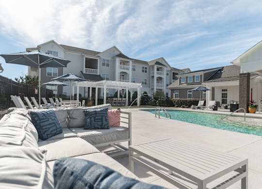 A poolside lounge area with white couches and a clear blue sky. at Concord Ridge Apartments, North Carolina, 28027