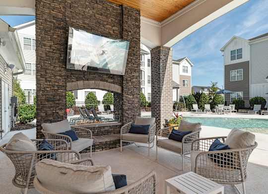 A patio with a fireplace and chairs is shown. at Concord Ridge Apartments, North Carolina