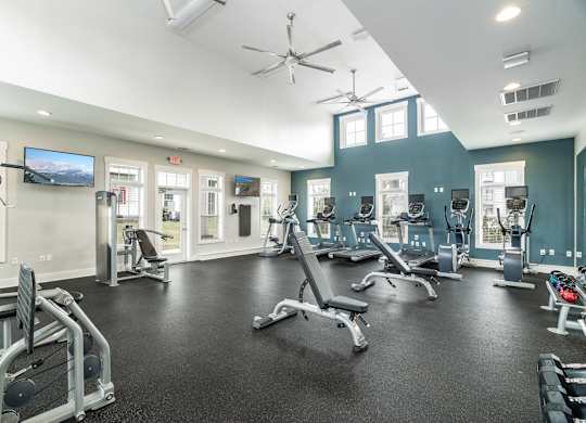 A spacious gym with a variety of equipment and a flat screen TV mounted on the wall. at Concord Ridge Apartments, North Carolina, 28027