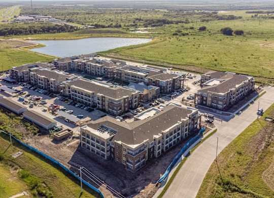 an aerial view of a group of buildings and a lake at Magnolia Grove Apartments, Terrell, 75160