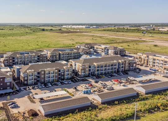 an aerial view of an apartment complex with a field in the background at Magnolia Grove Apartments, Terrell, Texas