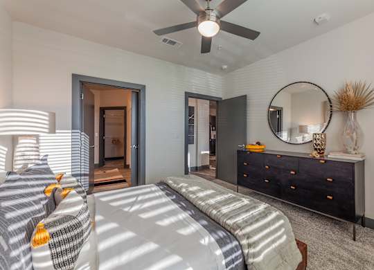 A bedroom with a bed, dresser, mirror, and a ceiling fan. at Magnolia Grove Apartments, Terrell, TX, 75160