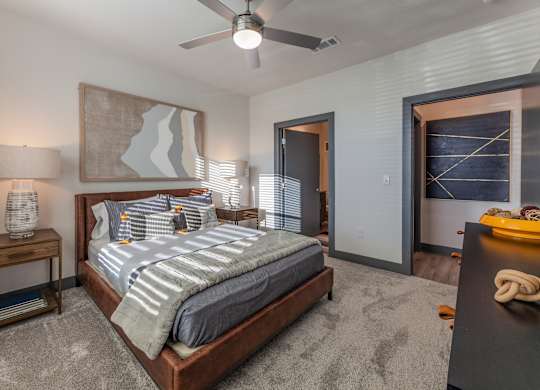 A bedroom with a large bed and a ceiling fan. at Magnolia Grove Apartments, Terrell, TX