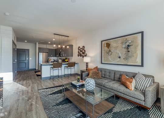 A modern living room with a grey couch and a large abstract painting on the wall. at Magnolia Grove Apartments, Terrell, Texas
