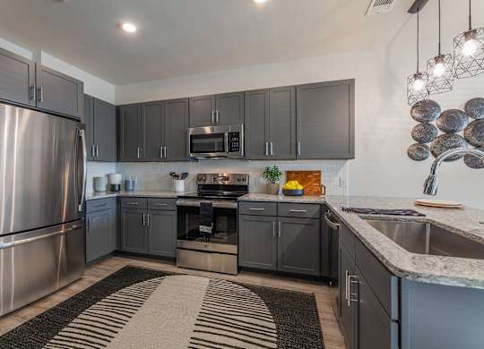 A modern kitchen with a stainless steel refrigerator and a black and white striped rug on the floor. at Magnolia Grove Apartments, Texas, 75160