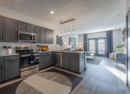 A modern kitchen with dark grey cabinets and a large island. at Magnolia Grove Apartments, Terrell, 75160