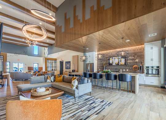 A modern living room with a large couch and a kitchen area in the background. at Magnolia Grove Apartments, Terrell