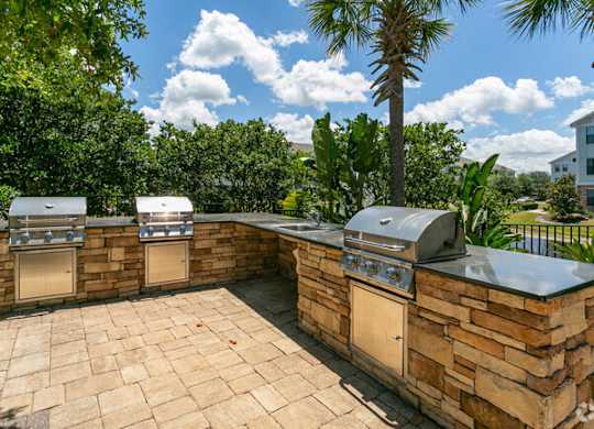 a stone patio with two grills on it at Terraces at Town Center, Jacksonville