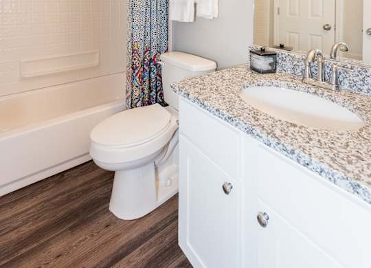 A white bathroom with a toilet, sink, and shower. at WildForest Apartments, Birmingham, 35209