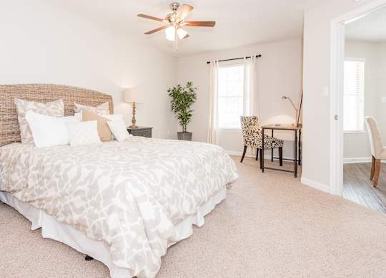 A bedroom with a large bed and a ceiling fan. at WildForest Apartments, Alabama