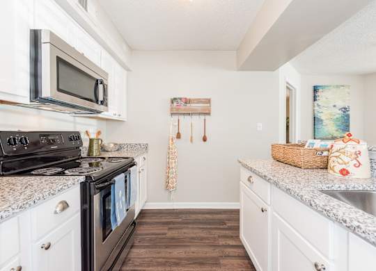 A kitchen with a black stove top oven and white cabinets. at WildForest Apartments, Birmingham, AL