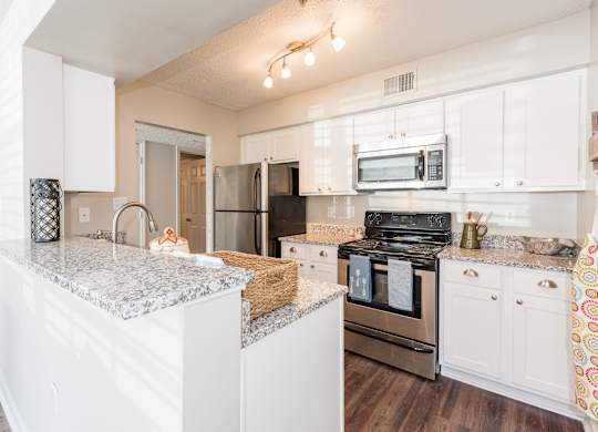 A kitchen with white cabinets and a granite countertop. at WildForest Apartments, Birmingham, Alabama