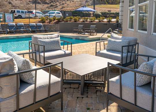 a patio with chairs and a table next to a pool at WildForest Apartments, Birmingham, AL, 35209