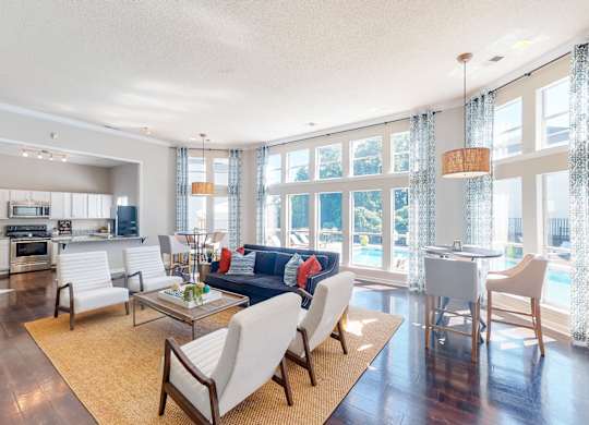 a living room with a couch and chairs and a kitchen with a large window at WildForest Apartments, Alabama, 35209