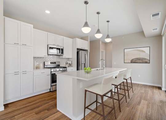 modern eat-in kitchen with island and stainless steel appliances at The Hallon Apartments, Hopkins