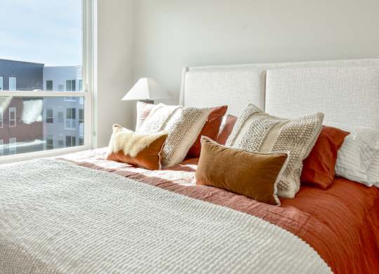 a bedroom with a large bed with pillows and a window at The Hallon Apartments, Hopkins