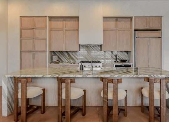 A kitchen with a marble countertop and wooden bar stools.