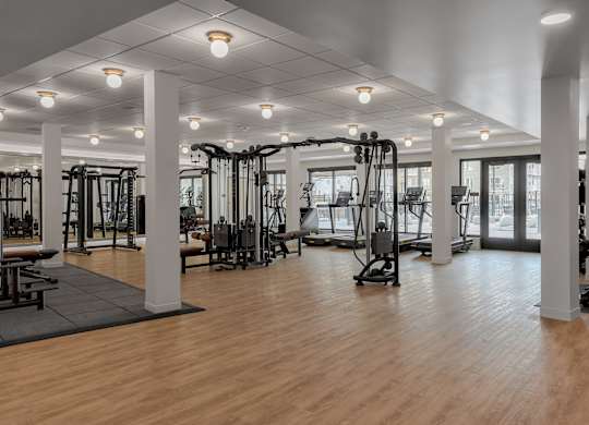 A gym with wooden floors and various exercise equipment.