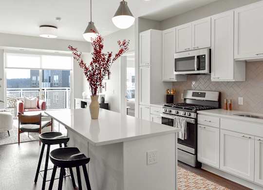 a kitchen with a large white island with three stools at The Hallon Apartments, Minnesota