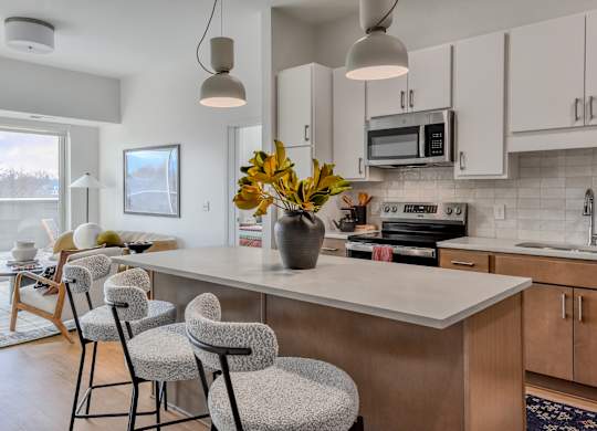A kitchen with a white countertop and a vase of yellow flowers on it.