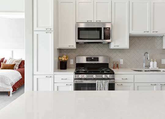 a kitchen with white cabinets and a stove and microwave at The Hallon Apartments, Hopkins