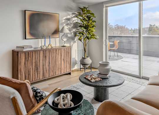 A living room with a wooden cabinet, a chair, a table, and a painting on the wall.