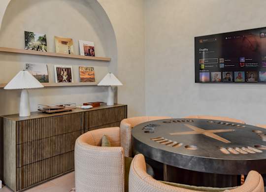 A modern living room with a round table and a flat screen TV mounted on the wall.