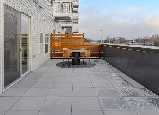 A patio with a table and chairs on a balcony.