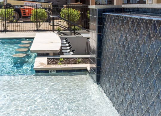 a swimming pool with a retaining wall and a water feature