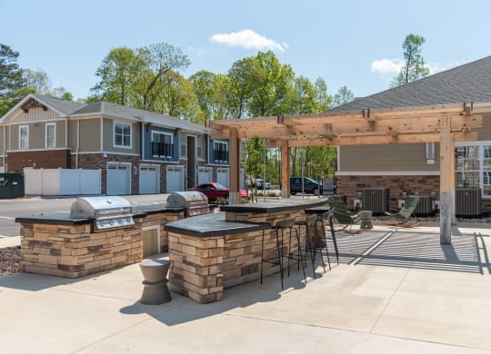 a patio with a bar and a grill in front of a house