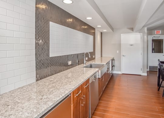 a long kitchen with granite counter tops and a sink